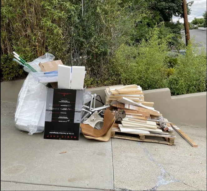 Curbside pile of cardboard, wood, and household junk staged for removal