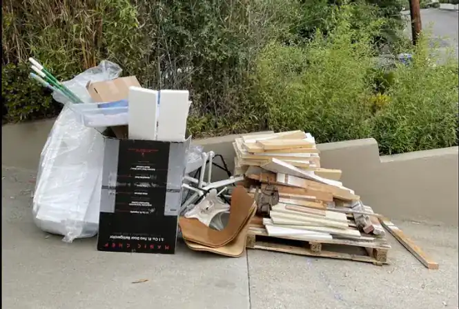 Curbside pile of cardboard, wood, and household junk staged for removal