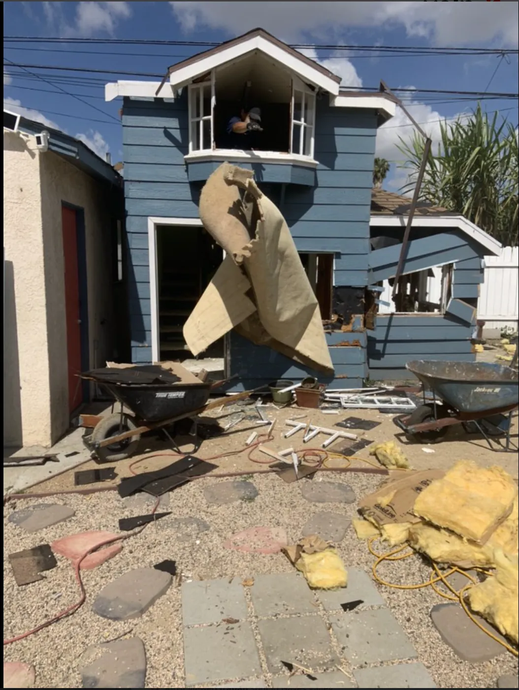Two-story house demolition in progress with carpet and debris removal