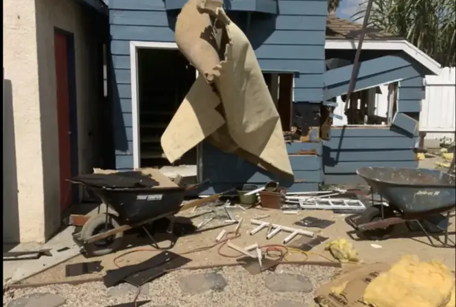 Two-story house demolition in progress with carpet and debris removal