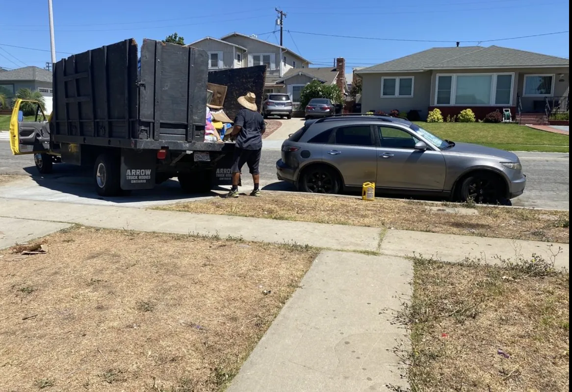 B Hauling crew member loading household items into a stake-bed hauling truck