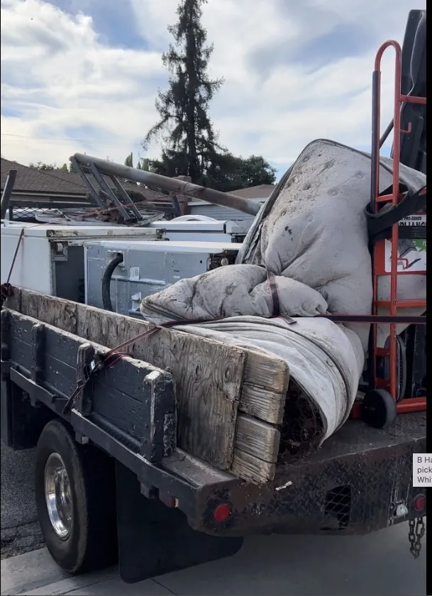 Junk hauling truck loaded with old furniture and mattresses