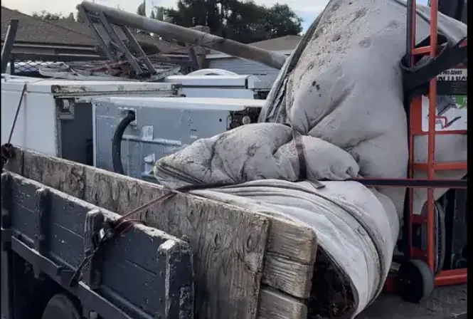 Junk hauling truck loaded with old furniture and mattresses